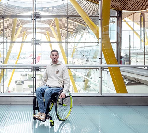 Chico en una silla de ruedas en el aeropuerto con un avión de Iberia en la zona exterior