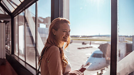 Tu viaje paso a paso Mujer en el aeropuerto viendo por la ventana el avión en el que viajará