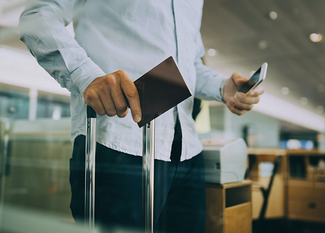  Man with his passport, mobile phone and carry-on bag at the airport