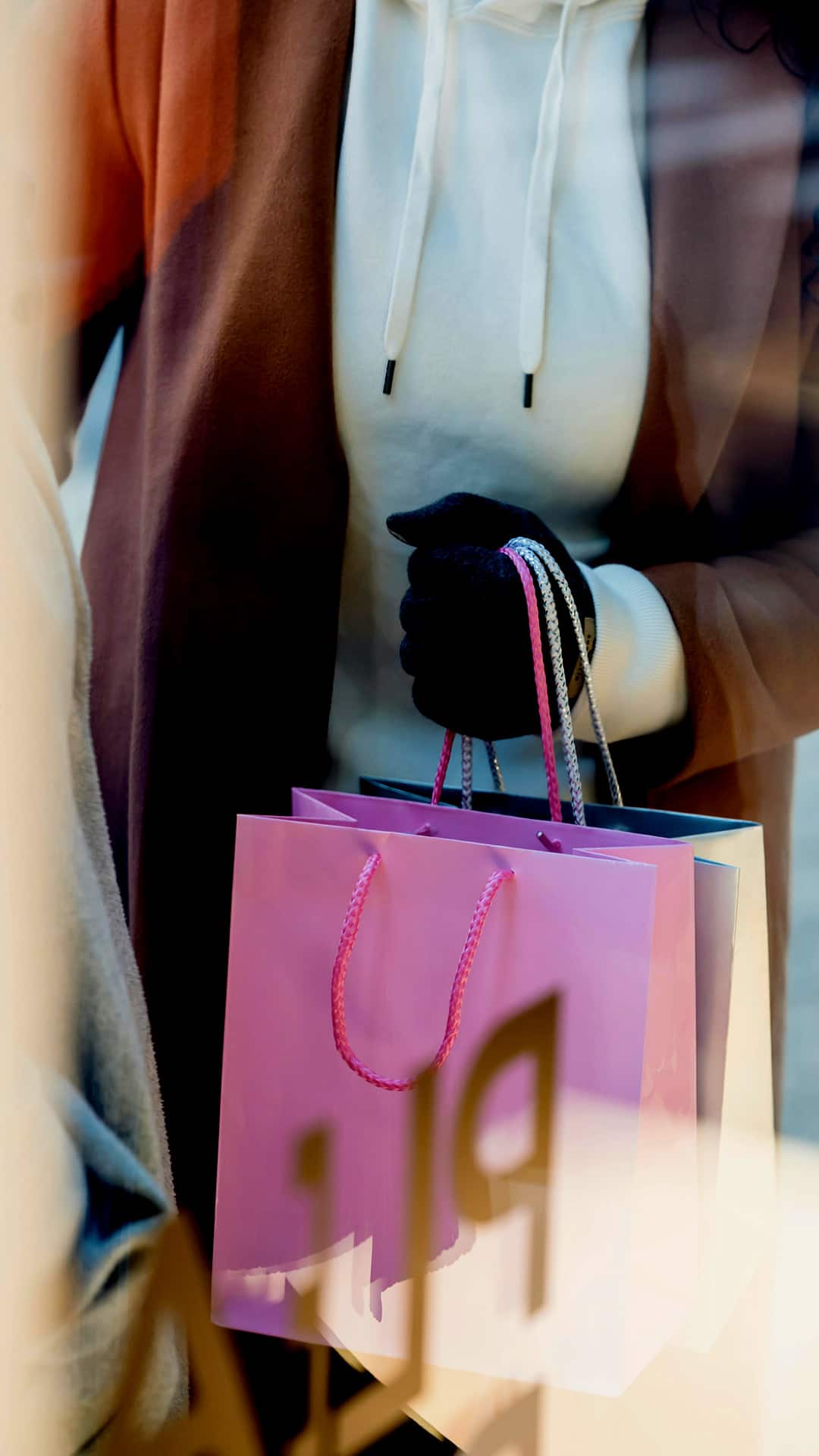 Detail of a person holding shopping bags in front of a shop window in Madrid