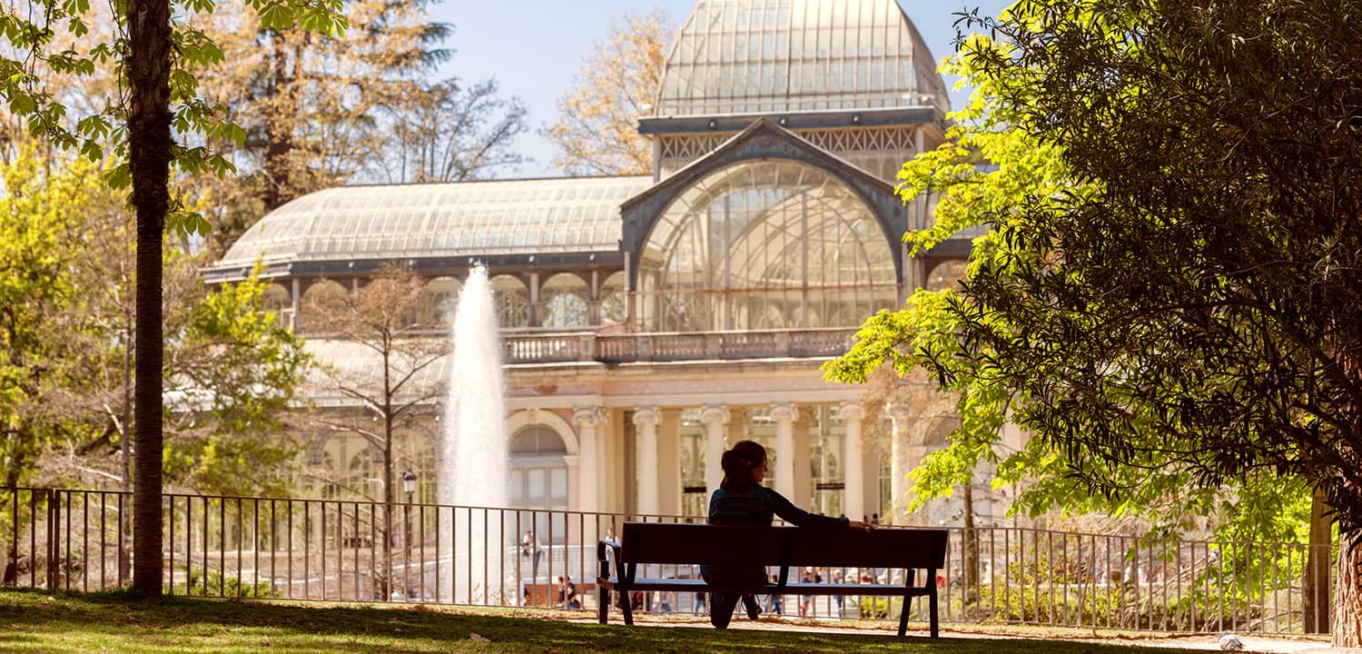 A woman sitting in front of the Crystal Palace in El Retiro, part of Madrid’s Landscape of Light