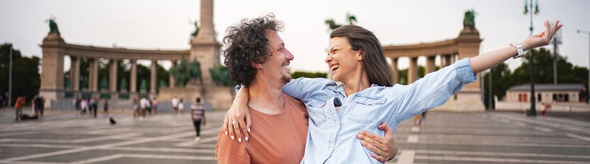 La imagen muestra a una pareja sonriente en un hermoso lugar al aire libre