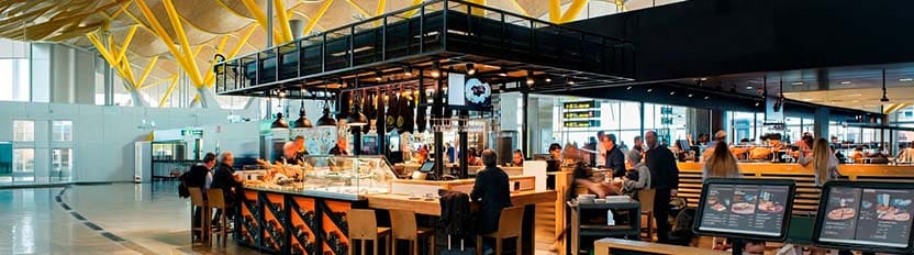 Una pareja de clientes compra en un puesto de comida en un aeropuerto.