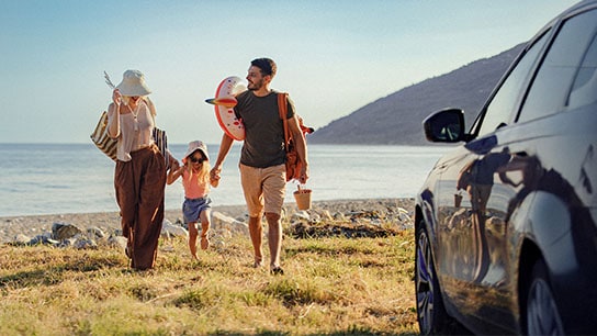 La imagen muestra una carretera curvada con un automóvil rojo conduciendo por ella, rodeada de vegetación y tierra.
