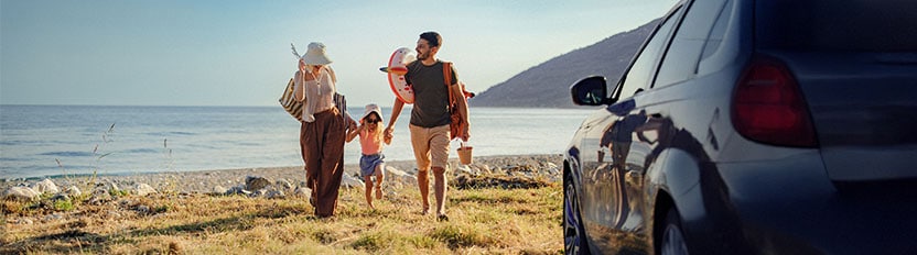 La imagen muestra una carretera curvada con un automóvil rojo conduciendo por ella, rodeada de vegetación y tierra.