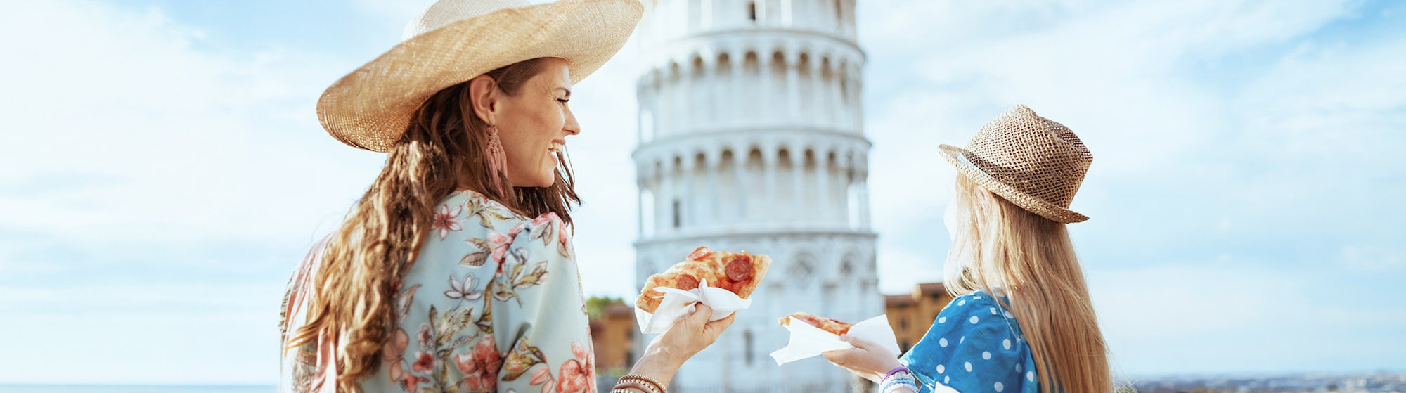 La imagen muestra a dos mujeres sonriendo mientras comen pizza